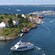 A boat filled with passengers sails through a series of rocky islets dotted with mariners homes